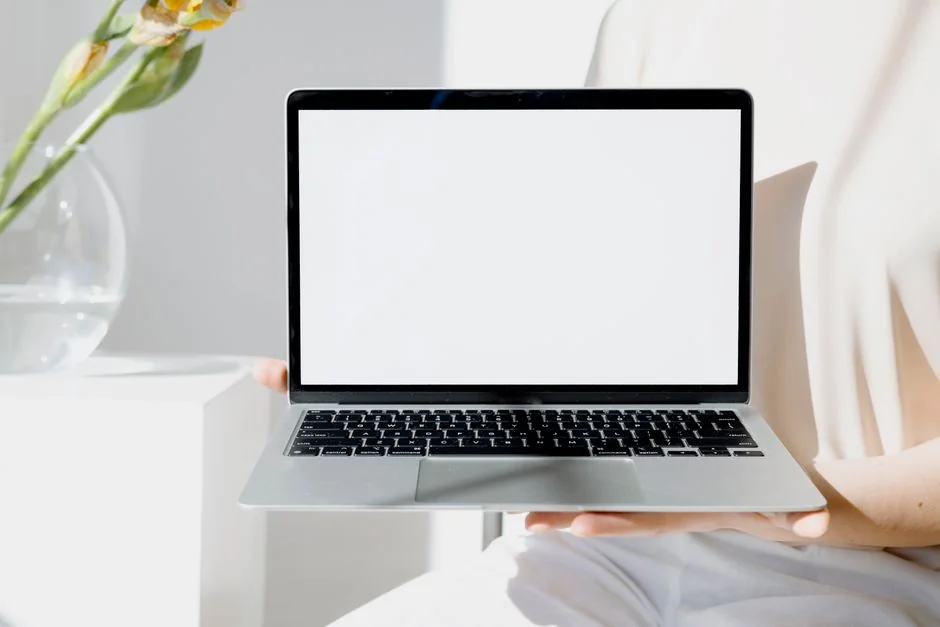 Open laptop showing a website screen on a wooden table in an outdoor terrace setting.